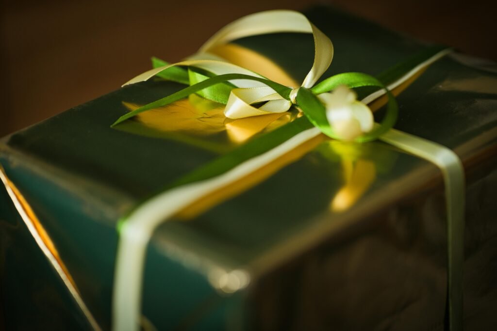 A beautifully wrapped gift box with green and gold ribbons, perfectly lit with a warm glow.