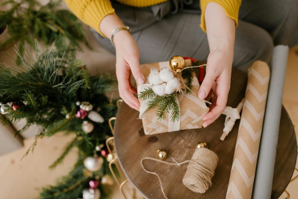 Hand-wrapped Christmas gift with decorative cotton and pine branches, ready for holiday celebration.